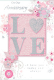 This anniversary card captures the feeling of long-lasting love in a soft and romantic design that would sit beautifully next to an anniversary bouquet delivered in Longford. The focal point is the word LOVE, prominently displayed in raised, softly shimmering glitter, with the letterforms appearing thick enough to cast the slightest shadow on the blush-pink backdrop. The texture of the glitter looks fine and smooth, more like a gentle frosting than a rough sparkle, inviting a tender touch. Surrounding the word is a graceful wreath of illustrated blossoms and vines, their lines delicate and flowing, reminiscent of floral patterns you might see sketched when planning a bespoke arrangement. The blooms themselves appear in shades of blush, mauve, ivory, and dove grey, echoing the gentle tones of a pastel bouquet chosen for an intimate celebration at home. The soft pink background has a velvety, almost cloudlike quality, and scattered across it are tiny decorative flourishes-swirls, petals, and subtle butterflies-that suggest motion without disturbing the calm mood. Silver accents add a refined shimmer, catching imaginary light as if the card were placed near a window overlooking a quiet Longford street. In elegant, understated script, the wording On Our Anniversary and I love you today and always is set among the florals, the letters slender and flowing, contributing to the sense of heartfelt sincerity. The whole composition feels like a whisper of affection captured on paper: gentle, thoughtful, and deeply personal, mirroring the sentiment behind sending hand-arranged anniversary flowers in the Longford area.